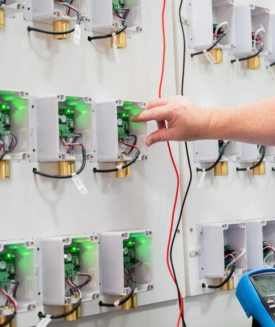 A Gas Detection Australia technician testing wall-mounted gas detectors with a multimeter